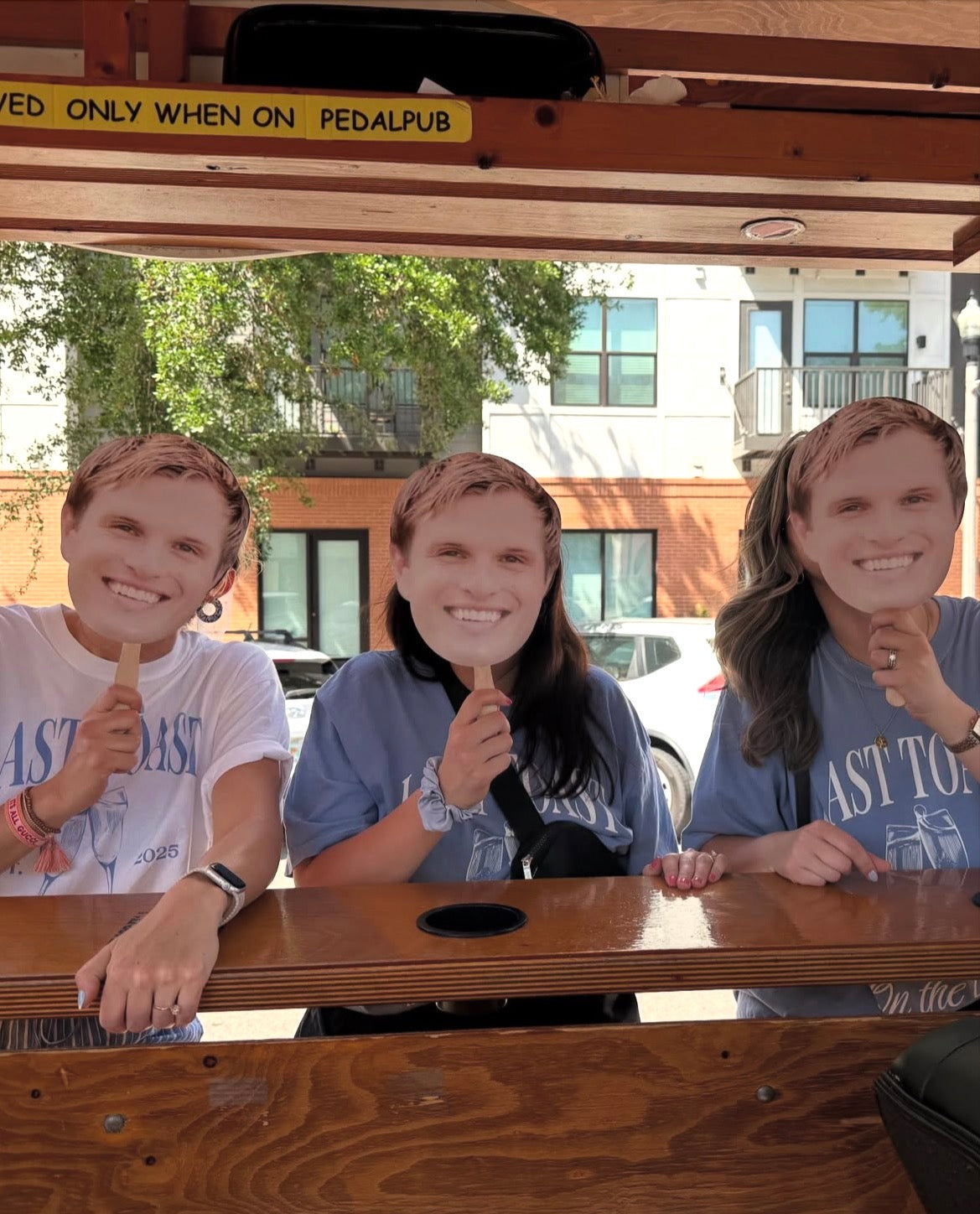 bachelorette group holding up groom cardboard face cutout on pedal pub bike in st pete 